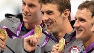 Michael Phelps holds up his gold medal after becoming the most successful Olympian of all time