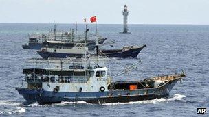 In this photo released by China's Xinhua, Chinese fishing vessels sail past a beacon of Zhubi Reef of the Spratly islands in South China Sea on 18 July, 2012