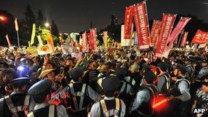 Protesters hold placards and shout slogans as they take part in a rally in front of Japan"s parliament