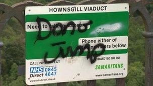 Sign on Hownsgill viaduct with phone numbers for The Samaritans and NHS Direct and the words "Don't jump" in spray paint