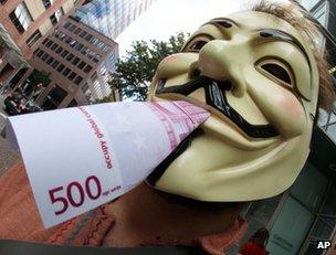 An activist of the occupy movement poses with a fake euro banknote in Frankfurt, home of the European Central Bank, 2 August