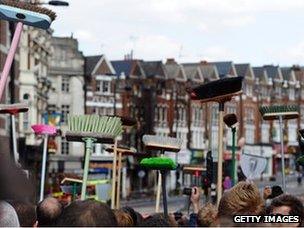 People holding brooms aloft on the street