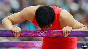 China's Liu Xiang kisses a hurdle after falling while competing in the men's 110m hurdles heats at the athletics event of the London 2012 Olympic Games on 7 August, 2012