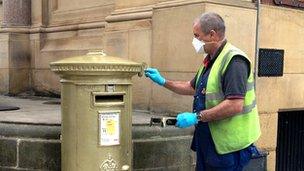 A Royal Mail employee applied a new layer of gold paint to the postbox