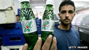 A man holding bottles of 7-Up