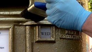 Man paints a post box gold