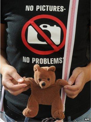 A Belarusian opposition activist holds a teddy bear as she wears a satirical t-shirt near a court in Minsk on 9 August