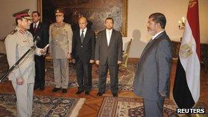 Egypt's President Mohammed Morsi (R) observes as new Defence Minister Abdel-Fattah al-Sisi receives his orders at the presidential palace in Cairo on Sunday