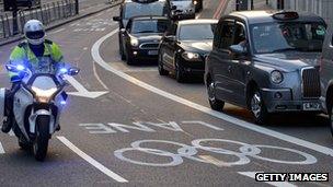 A police motorcyclist rides in a reserved Games Lane as taxis and commuters queue to leave central London