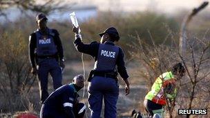 Policewoman helping a paramedic as he tends to the injured after police opened fire on striking workers at South Africa's Marikana platinum mine on 16 August 2012