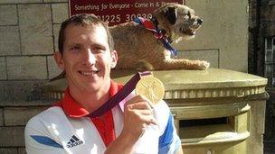 Gold medallist Ed McKeever poses for a photo with his gold medal beside a gold postbox in Bradford-on-Avon