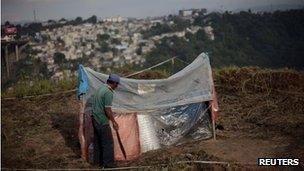 A child lies on grass at an irregular settlement beside Periferico Avenue in Guatemala City