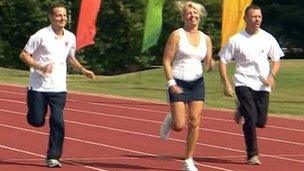 Three people running on athletics track