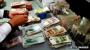 A clerk counting stacks of Chinese notes at a bank in Suining, southwest China's Sichuan province.