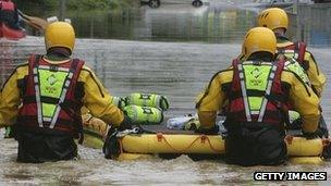 A fire rescue team with a dingy make their way down a flooded street