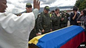 Colombian police officers and relatives pray over coffin of Cristian Flores, who was killed in Farc attack, August 2012