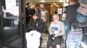 Demonstrators block the door of the DWP office