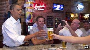 President Barack Obama buys a beer at a pub and grill in Cedar Falls, Iowa, while a campaign bus tour on 14 August 2012