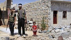 A child stands next to rebel soldiers outside Aleppo, Syria (4 Sept 2012)