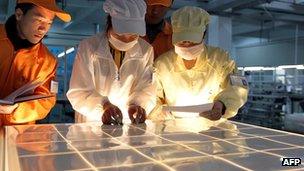 Workers inspecting solar panels at a factory in China