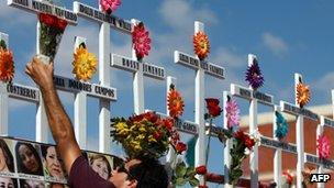 Relative of victims of the Casino Royale attack puts flowers on a cross during the commemoration of the first anniversary of the crime in Monterrey, Mexico, on 25 August 2012