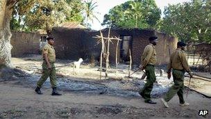 Police walk past the remains of houses which were burned down during clashes in Chamwanamuma village, Tana River delta, north of Mombasa in Kenya Friday, Sept. 7, 2012.