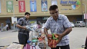 Small shop owners transport goods from shopping carts to their vehicle after shopping from a Bharti-Walmart store on the outskirts of Chandigarh, India, Sunday, Sept. 16, 2012.