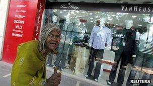 A beggar walks past a shop window with designer clothes in New Delhi's main business district in this October 29, 2009 file photo