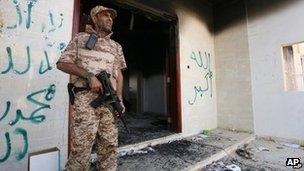 A Libyan soldier guards one of the buildings of the burnt out US consulate in Benghazi, Libya