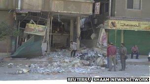 Residents look at a damaged store after clashes between the Free Syrian Army and forces loyal to Syria"s President Bashar al-Assad in Damascus September 15, 2012