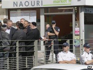 French police, members of the Jewish community and others stand outside the kosher store attacked in Sarcelles, 19 September