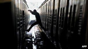 A passenger jumps from a train compartment to another at a railway station during a nationwide strike in Kolkata