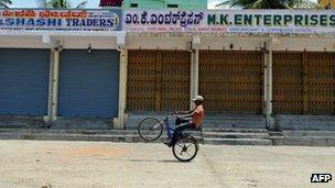 An Indian boy bikes past closed shops during a nationwide strike in Bangalore