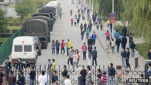 Workers walk past paramilitary police vehicles outside the Foxconn plant