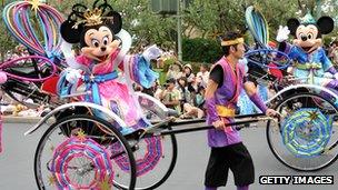 Minnie Mouse being pulled in a cart at a theme park