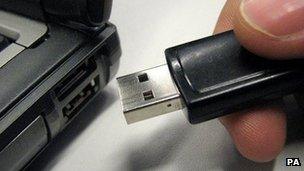 Man about to plug a USB stick into a laptop