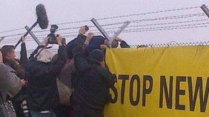 A protester scales the fence during a planned trespass at Hinkley Point