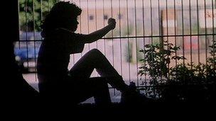 Silhouette of a girl looking through a park fence