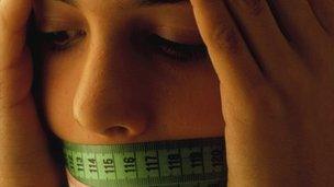 Girl with tape measure over her mouth