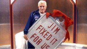 Jimmy Savile with giant Jim Fixed It For Us Badge