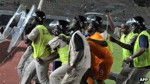 Riot police escort Ivorian players out of the stadium