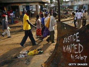 People walk past slogan in Kibera slum, Naoribi in 2008