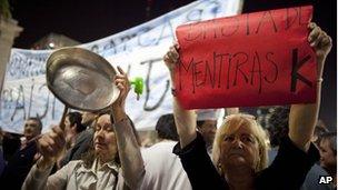 A woman holds a sign that reads in Spanish "Enough of K Lies," referring to Argentina's President Cristina Fernandez, as another bangs a pot in the Plaza the Mayo during a protest against government policies in Buenos Aires, Argentina, September 13, 2012.