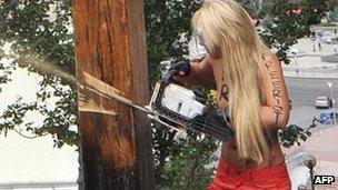 A Femen protester cuts down a cross in Kiev