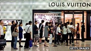 People queue outside a Louis Vuitton store in a Shanghai shopping mall