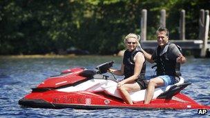 Mitt Romney rides on the back of a jet ski piloted by his wife Ann