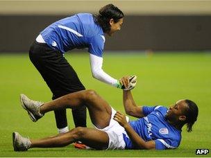 Didier Drogba helped up by Shanghai Shenhua goalkeeper Dong Guangxiang