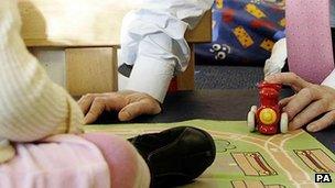 Man in shirt and tie playing with child's toys