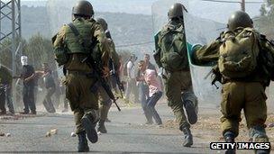 Palestinian protesters throw stones towards Israeli soldiers