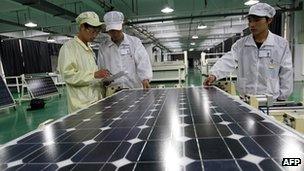 Workers inspect a solar panel in a Chinese factory